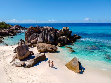 Çift, Anse Cocos 'un el değmemiş sahilleri boyunca, çarpıcı granit kayalar ve turkuaz sularla çevrili sakin bir yürüyüşün tadını çıkarıyor. La Digue, Seyşeller 'in cennetine mükemmel bir kaçış.