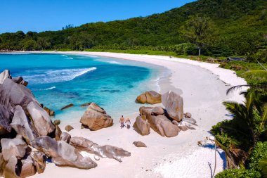 Ziyaretçiler, dev granit kayalar ve kristal berrak sularla çevrili Anse Cocos plajları boyunca yürüyorlar. La Digue Seyşeller