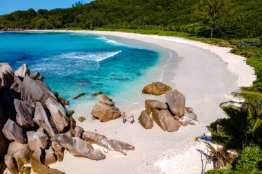 Bir çift Anse Cocos plajına kaçar, yumuşak beyaz kumların kristal berrak sularla buluştuğu yere. La Digue, Seyşeller tropik cennetinde sükuneti ve doğal güzelliği tecrübe edin..