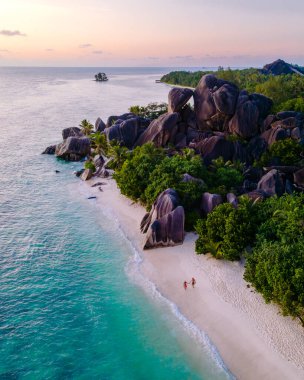 Kristal berraklığında turkuaz sular Anse Source d 'Argent sahilinin tozlu beyaz kumlarına nazikçe çarpar. Bereketli yeşillik, yüksek granit kayaları, La Digue, Seyşeller 'de tatilde olan bir çifti çevrelemektedir.