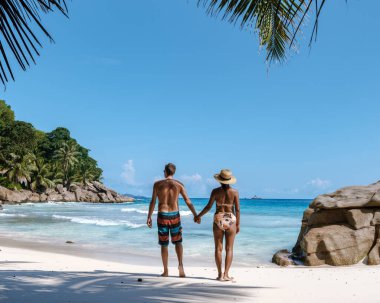 Anse Patates 'in yumuşak kumları boyunca, tropikal güneşin ve canlı okyanus manzarasının tadını çıkararak güzel bir çift yürüyüş yapar. Bereketli palmiye ağaçları çerçevesi Bu mükemmel kaçış, La Digue, Seyşeller