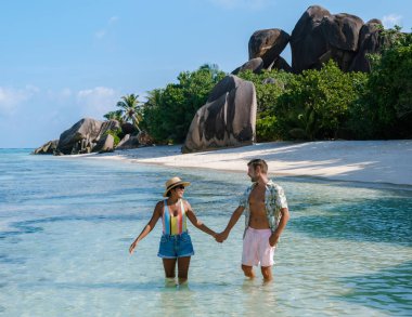 Anse Source d 'Argent plajının nefes kesici arka planına karşı durgun sularda el ele bir kaç gezinti. Yeşillik ve eşsiz kaya oluşumları La Digue, Seyşeller