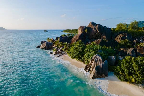 Yumuşak dalgalar güneş batarken Anse Kaynak d 'Argent sahillerine hafifçe vurur. Bereketli yeşillik ve çarpıcı granit kayalar Seyşeller 'de tropik bir cennet yaratır..