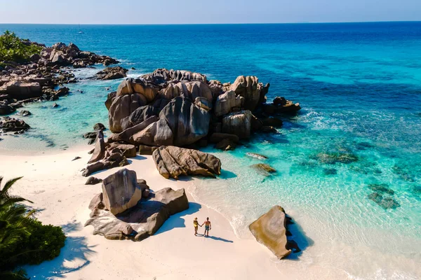 İki arkadaş, güneşli bir günde turkuvaz suları ve çarpıcı kaya oluşumlarıyla çevrili La Digue, Seyşeller 'deki Anse Cocos plajında dinleniyor..