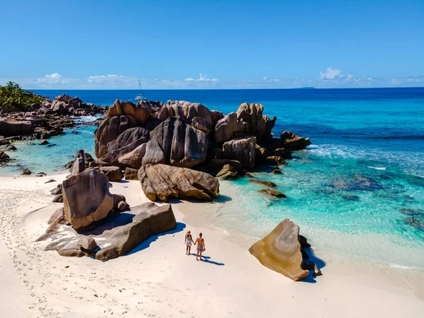 Çift, Anse Cocos 'un el değmemiş sahilleri boyunca, çarpıcı granit kayalar ve turkuaz sularla çevrili sakin bir yürüyüşün tadını çıkarıyor. La Digue, Seyşeller 'in cennetine mükemmel bir kaçış.