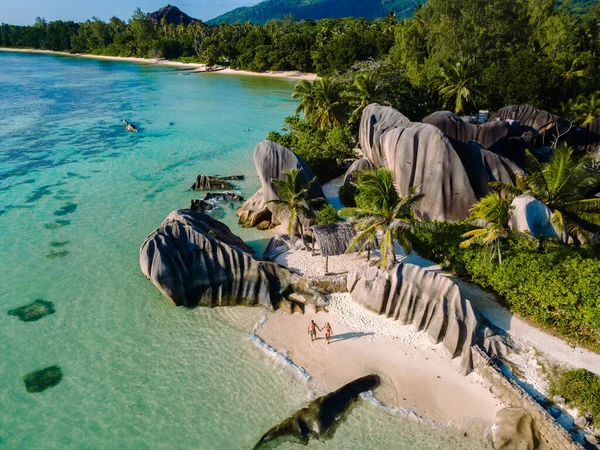 La Digue, Seyşeller 'deki Anse Source d' Argent plajının çarpıcı güzelliğini deneyimleyen bir çift, turkuaz sularda devasa granit kayalara çarpıyor..