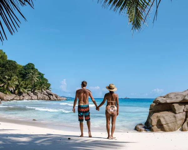 Anse Patates 'in yumuşak kumları boyunca, tropikal güneşin ve canlı okyanus manzarasının tadını çıkararak güzel bir çift yürüyüş yapar. Bereketli palmiye ağaçları çerçevesi Bu mükemmel kaçış, La Digue, Seyşeller