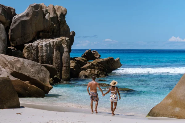 Güzel bir çift, Seyşeller 'deki Anse Cocos plajının el değmemiş beyaz kumları boyunca romantik bir yürüyüş yapar. Turkuaz sular ve çarpıcı kaya oluşumları tropik bir cennet yaratır..