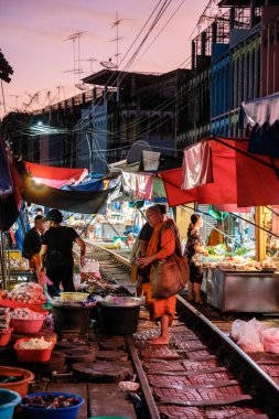 5 Aralık 2025 'te Tayland' daki Maeklong Demiryolu Pazarı 'nda satıcılar tren yolu boyunca tezgahlarını hazırlarken tren pazarının hareketli atmosferini deneyimleyin..