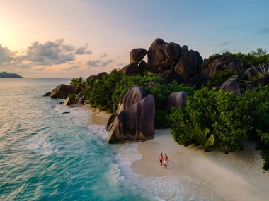 Çift, Anse Source d 'Argent' ın el değmemiş kıyıları boyunca yüksek granit kayalar ve yemyeşil ağaçlarla çevrili olarak yürüyor. Bu çarpıcı sahil Seyşeller 'e huzurlu bir kaçış sunuyor..