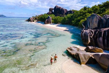 İki gezgin, La Digue, Seyşeller 'deki Anse Source d' Argent sahillerinde el ele dolaşır. Etrafı eşsiz kaya oluşumları ve kristal berrak sularla çevrilidir.