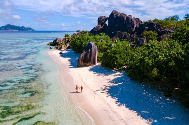 Çift el ele yürür Anse Kaynağı d 'Argent La Digue, Seyşeller' in el ele yükselen granit kayalar ve parlak turkuaz okyanuslarla çevrili el ele.