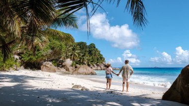 Anse Patates, La Digue, Seyşeller 'de sakin bir sahne. Birkaç çift el ele gezip doğal güzelliğin ortasındaki güneşli tropikal kaçışın tadını çıkarıyorlar..