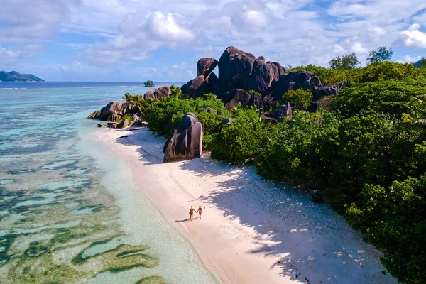 Kristal berrak sular ve eşsiz granit kayalar Anse Source d 'Argent plajında pitoresk bir manzara yaratır. Çift, yumuşak kumda geziniyor, La Digue Seyşeller 'in dingin güzelliğinin tadını çıkarıyor..