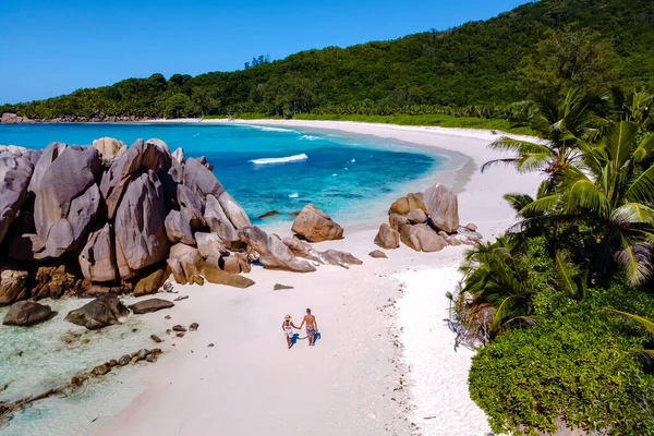 İki gezgin, yemyeşil ve çarpıcı kaya oluşumlarıyla çevrili Anse Cocos plajı boyunca el ele yürüyorlar. Cennet plaj aşıkları için mükemmeldir..