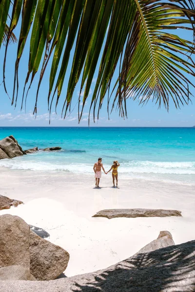 Seyşeller 'de Anse Georgette' in el değmemiş kumları boyunca romantik bir gezinti yapan iki yolcu. Turkuaz sular ve yemyeşil palmiye ağaçları mükemmel bir tropikal kaçış sağlar..