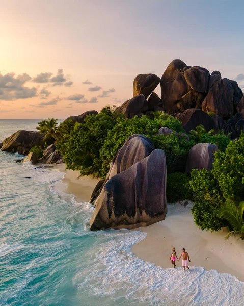 Anse Source d 'Argent' ın tozlu sahillerinde, renkli bir gün batımının altında sahil boyunca yürüyen iki yolcu gibi yumuşak dalgalar tur atıyor. Bu tropik cenneti eşsiz granit kayalar çerçeveler. La Digue, Seyşeller