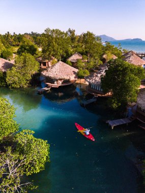 Tayland 'daki Koh Phayam Adası' nın dingin cazibesini deneyin. Bir kano, yemyeşil ve geleneksel sazdan çatı köşkleriyle çevrili sakin suları keşfeder..