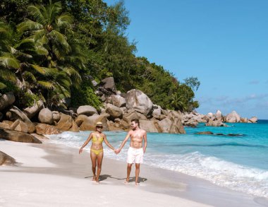 Bir çift Praslin Seyşeller 'deki Anse Georgette sahilinde romantik bir yürüyüş yapıyor. Bereketli palmiye ağaçları ve gök mavisi sular tatilciler için mükemmel bir tropik cennet yaratır..