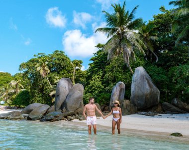 Çift, Mahe Seyşeller 'deki Anse Royale sahilinin el değmemiş kıyılarında romantik bir gezinti yapıyor. Turkuaz sular ve yemyeşil yemyeşil rahatlama ve aşk için cennet gibi bir ortam yaratır..