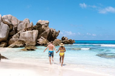 La Digue, Seyşeller 'deki Anse Cocos kumsalında güzel bir çift birlikte dolaşır..