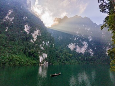 Tayland 'daki Khao Sok Ulusal Parkı' nın barışçıl güzelliğini tecrübe edin. Sabahın erken saatlerinde güneş durgun sulara altın ışınlar saçar..