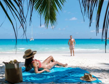 Yumuşak dalgalar, Anse Georgette Sahili 'nde güneşli bir günün tadını çıkarırken, etrafı palmiye ağaçları ve turkuaz sularıyla çevrili. Praslin, Seyşeller 'de tatilciler için mükemmel bir kaçış yolu.