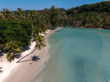 Ziyaretçiler, temiz turkuaz suların ılık güneşin altında yumuşak beyaz kumlarla buluştuğu Tayland 'ın Koh Kood kentindeki Khlong Hin Sahili' nde sakin bir günün tadını çıkarıyorlar. Yeşillik serin bir atmosfer yaratır..