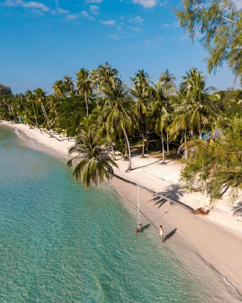 Ziyaretçiler Koh Kood, Tayland 'daki Khlong Hin Sahili' nin sakinliğinin tadını çıkarıyorlar. Güneş yumuşak kum ve turkuaz suyun üzerinde ışıl ışıl parlıyor, rüzgarda hafifçe sallanan gür palmiyelerle çevrili..