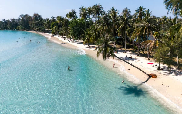 Ziyaretçiler, Tayland 'ın Koh Kood kentindeki Khlong Hin Sahili' nde güneşli bir günün tadını çıkarıyorlar. Dalgalar kıyıya vuruyor ve bereketli palmiye ağaçları dinlenmek ve eğlenmek için tropik bir cennet sunuyor..