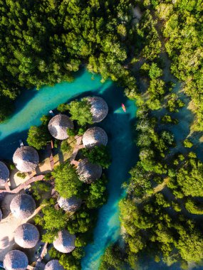 Tayland 'daki Koh Phayam Adası' nın nefes kesen manzarasını keşfedin. Canlı yeşillik ve sakin sular arasında yuva yapmış eşsiz yuvarlak bungalovlar. Rahatlama ve macera arayanlar için mükemmel..
