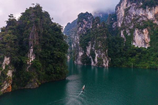 Yüksek kireçtaşı kayalıkları ve yoğun ormanların arasına yerleşmiş dingin bir tekne, Cheow Lan Gölü 'nün turkuaz sularında süzülüyor. Khao Sok Tayland