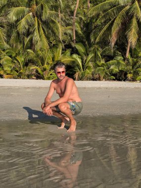 Bir gezgin Ao Jark Sahili, Koh Kood, Tayland 'ın sakin atmosferinin tadını çıkarır. Bereketli palmiye ağaçları ve parlak sularla çevrili bu an, mükemmel bir tropikal bayramın özünü yakalar..