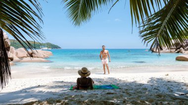 Anse Georgette sahilinde turkuaz suları ve altın kumları var. Bir çift tatilin tadını çıkarırken, bir kişi güneşlenirken diğeri de yakınlarda duruyor. Praslin, Seyşeller