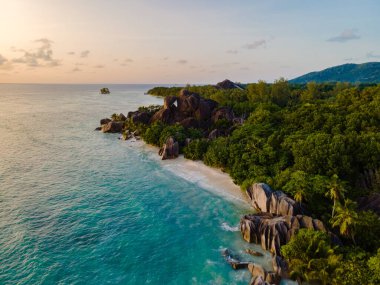 Dalgalar yavaşça Anse Kaynağı d 'Argent' taki muhteşem granit kayalara ve yumuşak kumlu plajlara çarpıyor. Güneş yemyeşil çimlerin ardında batıyor. Muhteşem bir tropik cennet yaratıyor. La Digue, Seyşeller