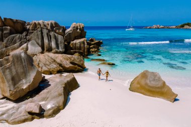 Çift, La Digue, Seyşeller 'deki Anse Cocos plajı boyunca romantik bir yürüyüş yapmayı seviyor. Kristal berrak sular ve görkemli kaya oluşumlarıyla bu cennet rüya gibi bir tatil için mükemmel..
