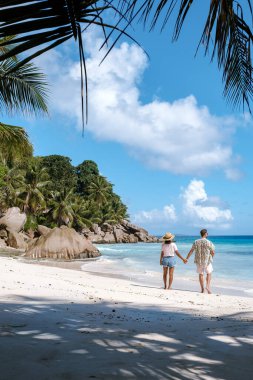 Huzurlu bir an, Anse Patates, La Digue Seyşeller 'in el ele el ele yürüyen sahillerini yakalar. Gök mavisi sular ve yemyeşil palmiye ağaçları muhteşem bir tatil cenneti yaratır..
