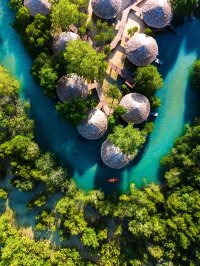 Tayland 'daki Koh Phayam Adası' nın sakin cazibesini keşfedin. Yeşilliklerin arasına yerleştirilmiş eşsiz sazdan çatı kulübeleri. Dalgalı mavi sular manzarada esiyor, rahatlamaya davet ediyor..