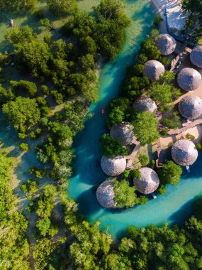 Zarif yeşillik, büyüleyici kulübelerin doğayla harmanlandığı Koh Phayam Adası Tayland 'daki sakin bir nehri çerçeveler. Bu huzurlu sahne, sersemletici manzaraların arasına rahatlama ve macera davet ediyor..