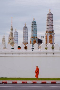 Bangkok, Tayland, 19 Kasım 2025. Turuncu cüppeli bir keşiş ikonik Wat Phra Kaew 'in yanında yürürken huzurlu bir an yaşanıyor..
