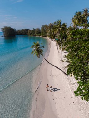 Khlong Hin Sahili 'nin yumuşak, beyaz kumları boyunca el ele dolaşan bir çift erkek ve kadın, Tayland' ın Koh Kood kentinin nefes kesici güzelliğinin tadını çıkarıyorlar..