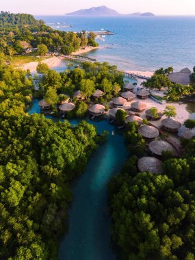 Tayland 'daki Koh Phayam Adası' nın el değmemiş güzelliğini keşfedin, kırsal kulübelerin canlı mangrovlarla uyumlu bir şekilde harmanlandığı, sakin mavi suların ortasında huzurlu bir geri çekilme sunan.