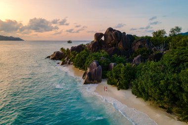 Ziyaretçiler Anse Source d 'Argent plajının sakin atmosferinin tadını çıkarırken dalgalar yavaşça kıyıya vuruyor. La Digue, Seyşeller