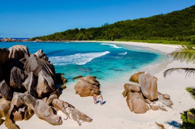 Altın kumlar, Seyşeller 'deki Anse Cocos plajında turkuaz sularla buluşur. Gezginler güneşli bir günün tadını çıkarıyorlar. Güneşin tadını çıkarıyorlar. Büyüleyici kaya oluşumları ve yemyeşil alanlar arasında..