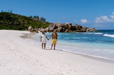 Çift, La Digue, Seyşeller 'deki Anse Cocos plajında el ele yürür..
