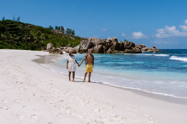 Çift, La Digue, Seyşeller 'deki Anse Cocos plajında el ele yürür..