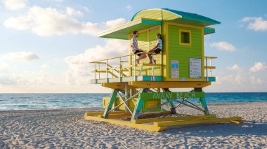 Miami sahili boyunca uzanan altın kumlar, canlı bir cankurtaran kulesinin tepesinde güneş ve okyanus esintisi altında duruyor. Bu resim sahnesi mükemmel bir sahil tatilinin özünü yansıtıyor..