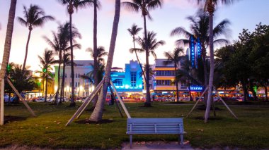 Miami, Florida, 19 Nisan 2019. Ziyaretçiler Miami Plajı 'nda güneşli bir akşamın keyfini çıkarıyorlar. Canlı restoranlar ve palmiye ağaçlarına altın renkler döküyorlar..