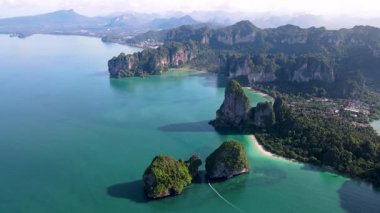 Tayland, Krabi 'deki Railay Sahili' nin nefes kesici güzelliğini tecrübe edin. Berrak mavi gökyüzünün altında canlı turkuaz suları ve dramatik kireçtaşı kayalıkları sergiliyor..