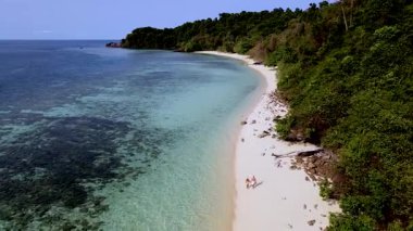 Turkuaz renkli bir okyanus, Koh Kradan 'da berrak su, Trang, Tayland' da tropikal bir ada ve tropik bir adanın önünde bir mercan resifi, Tayland sahilinde yürüyen bir çift.